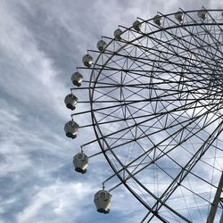 Low angle view of ferris wheel against cloudy sky