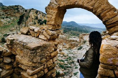 Side view of woman standing by old ruin