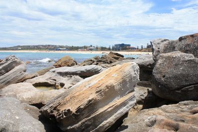 Stack of logs by sea against sky