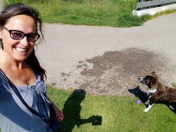 Portrait of young woman with dog on grass