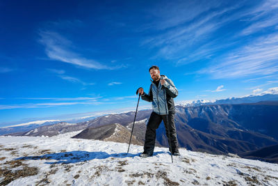 View of man standing on snowcapped mountain against sky
