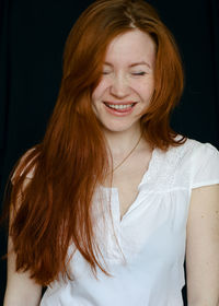 Portrait of smiling young woman against black background