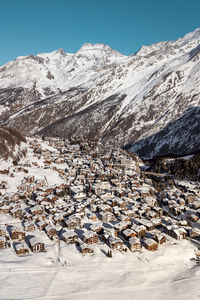 Aerial view of snow covered buildings against mountain