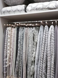 View of a wardrobe with woolen blankets hanging on hangers and pillows and blankets on the shelves.