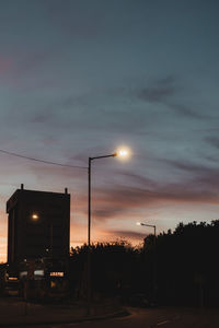 Cars on street against sky during sunset