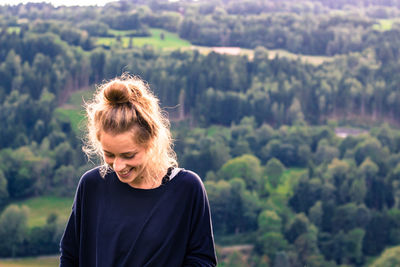 Front view of smiling woman standing against mountain