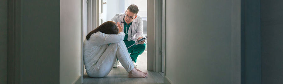 Doctor consoling depressed woman at hospital
