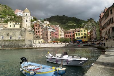 Boats in canal by buildings against sky