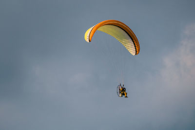 Low angle view of person powered paragliding in sky