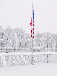 View of flag on snow covered field against sky