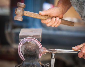 Blacksmith hands shaping horseshoe with hammer in workshop