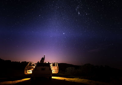 Cars on field against sky at night