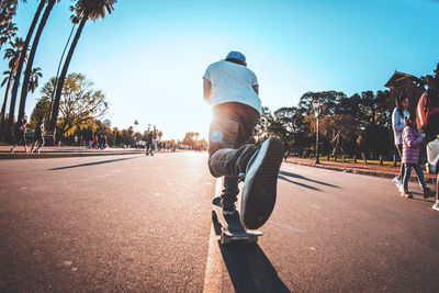 Rear view of man skateboarding on road