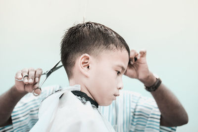 Barber cutting boy hair at salon