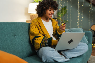 Young woman using laptop while sitting on sofa at home