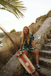 Young happy female with long board skate at sunset