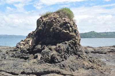 Rock in sea against sky