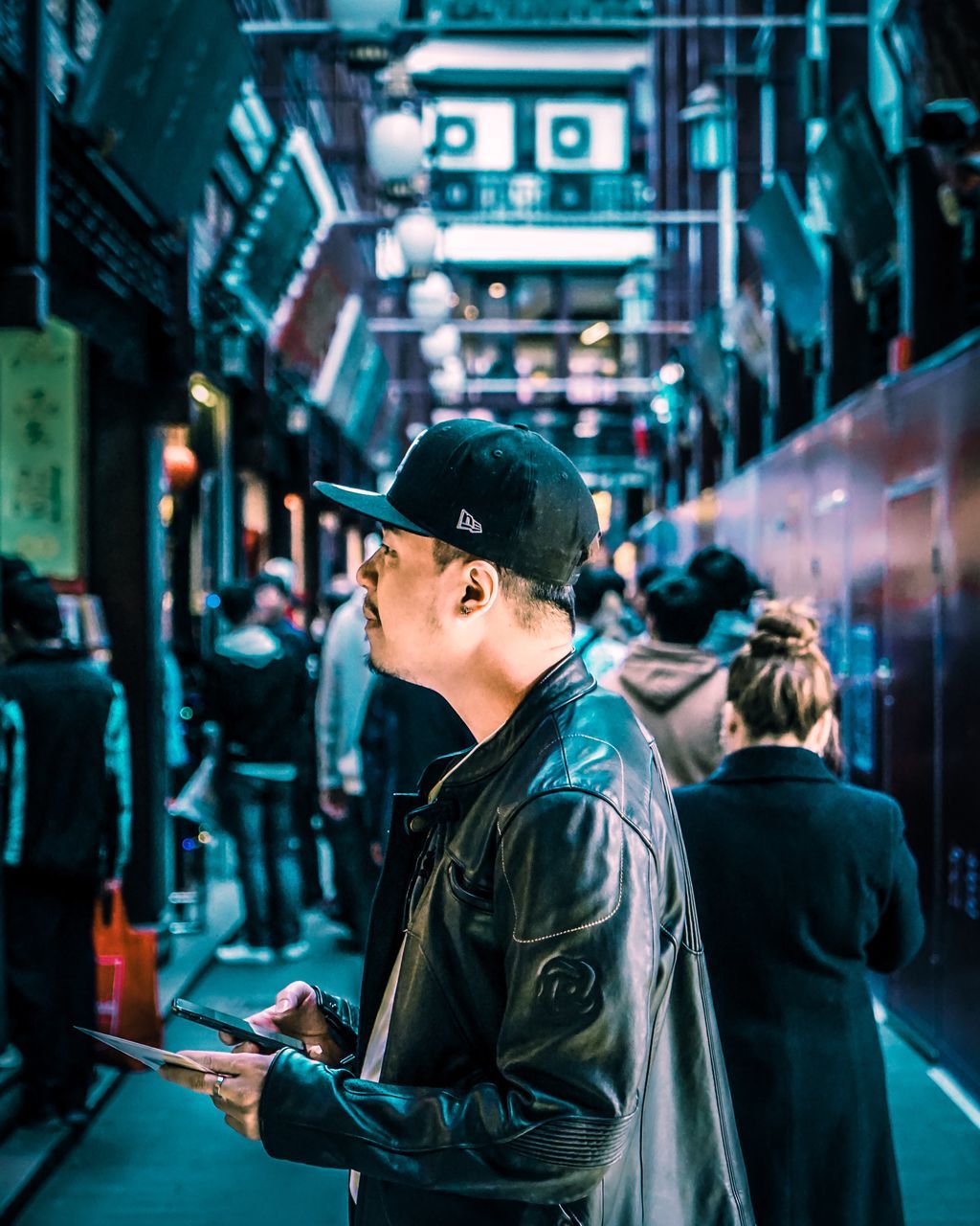 one person, architecture, real people, incidental people, built structure, technology, side view, lifestyles, waist up, focus on foreground, young adult, illuminated, looking, city, standing, glasses, building exterior, clothing, outdoors