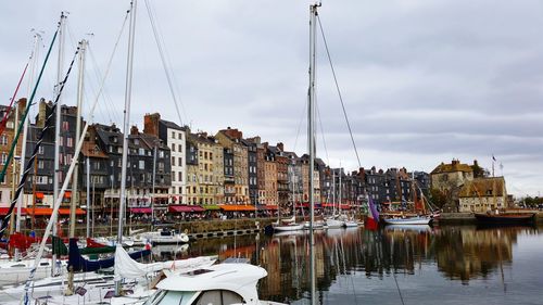 Boats moored in amusement park by city against sky