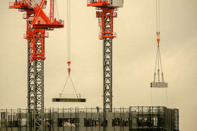 Cranes at construction site against sky