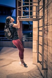 Side view of woman hanging on metal