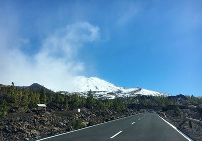 Road by mountains against sky