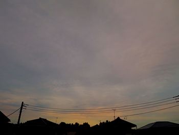 Low angle view of silhouette electricity pylon against sky during sunset