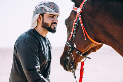 Man looking at horse while standing in desert