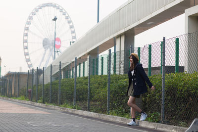 Rear view of woman standing with umbrella against sky in city