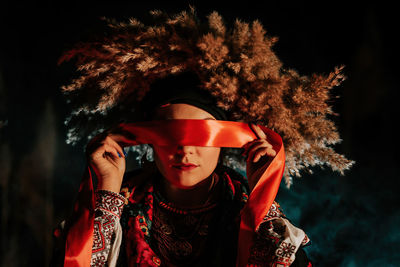 Portrait of young woman standing against black background