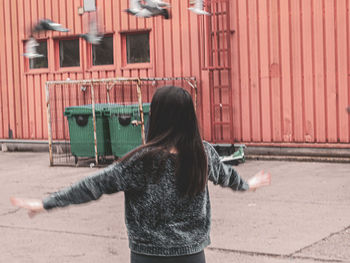 Rear view of woman standing against building in city