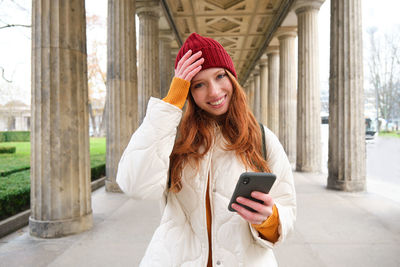 Young woman using mobile phone while standing in city