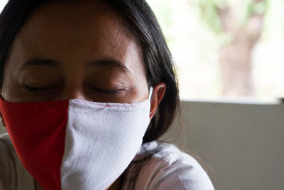 Close-up portrait of a woman wearing red and white colored mask. 