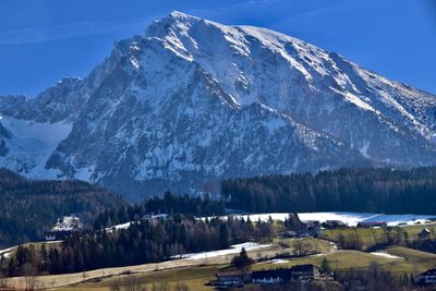 Scenic view of farm house, forests and snowcapped mountains against sky