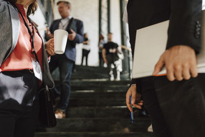 Mature businesswoman holding coffee mug while discussing with male colleague during networking event