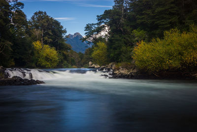 Scenic view of waterfall in forest against sky