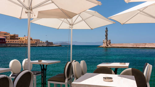 Chairs and tables at restaurant against sea