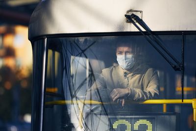 View of driver wearing flu mask sitting in bus