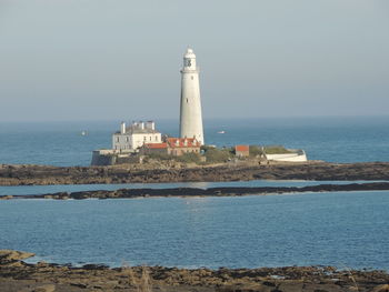 Lighthouse by sea against sky