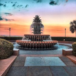 Water fountain in swimming pool against sky during sunset