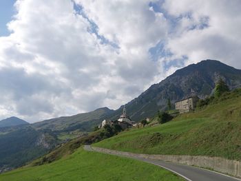 Empty road leading towards mountains against cloudy sky