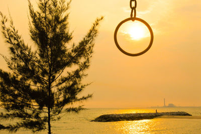 Silhouette tree by sea against sky during sunset