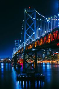 Illuminated bridge over river at night