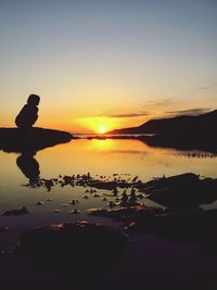 Silhouette man at beach against clear sky during sunset