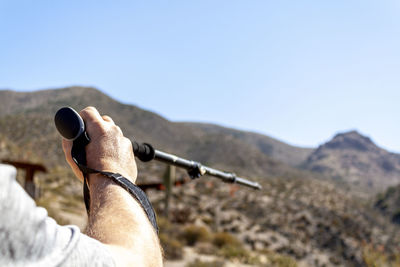 Midsection of man holding mountain against sky