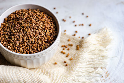 Bowl full of organic raw buckwheat on wooden table with towel