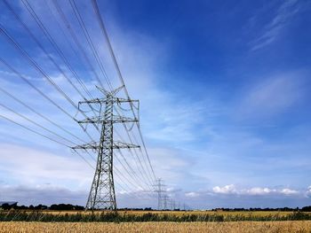 Low angle view of electricity pylon on field against sky