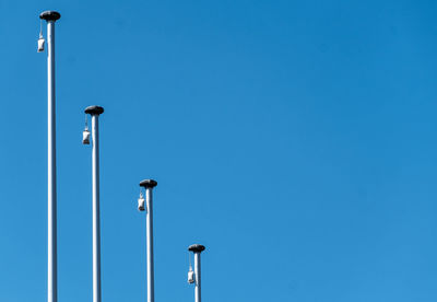 Low angle view of poles against clear blue sky