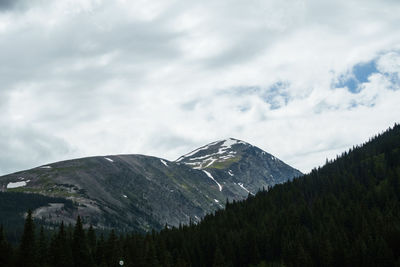 Scenic view of snow covered mountains against cloudy sky