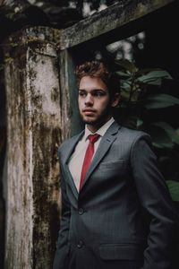 Portrait of young man standing against wall